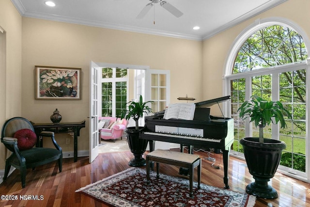 living area with ceiling fan, baseboards, crown molding, and wood finished floors