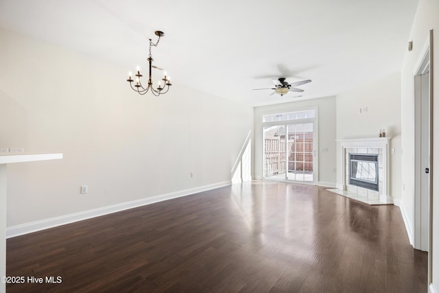 unfurnished living room featuring ceiling fan with notable chandelier, dark hardwood / wood-style flooring, and a fireplace