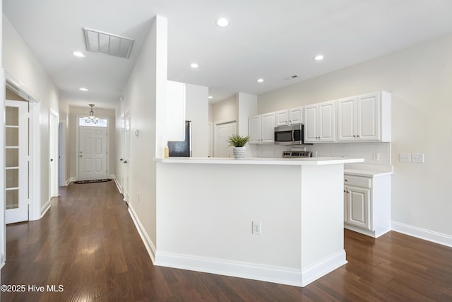 kitchen with backsplash, white cabinets, dark hardwood / wood-style floors, and kitchen peninsula