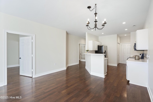 kitchen featuring white cabinets, appliances with stainless steel finishes, decorative light fixtures, dark hardwood / wood-style floors, and a chandelier