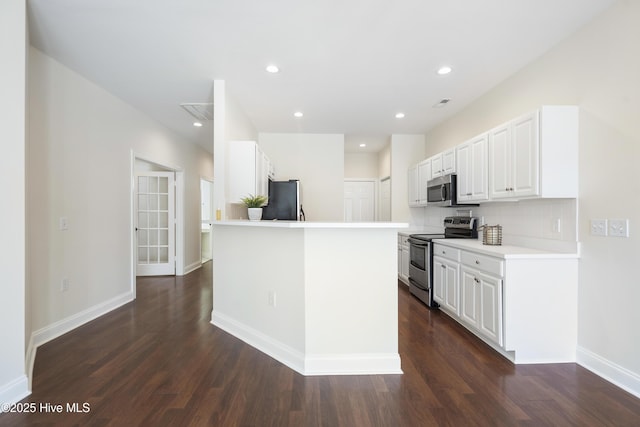 kitchen featuring backsplash, white cabinets, dark hardwood / wood-style floors, a kitchen island, and stainless steel appliances