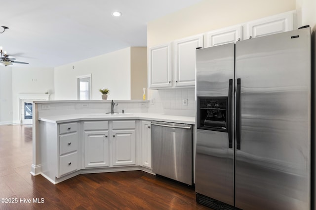 kitchen featuring kitchen peninsula, sink, white cabinets, dark wood-type flooring, and stainless steel appliances