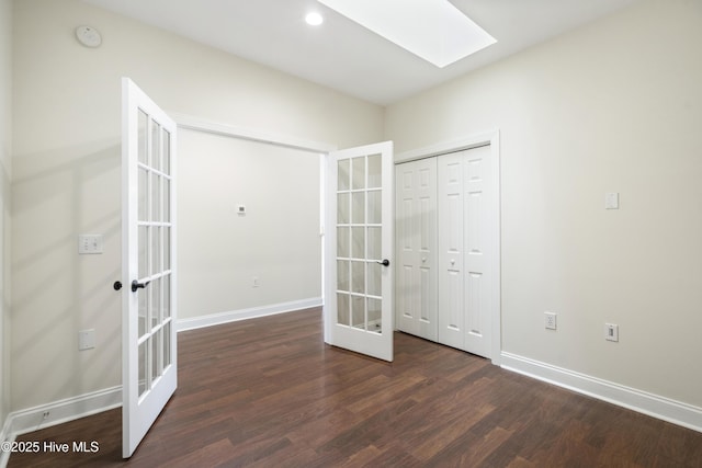 interior space with a closet, a skylight, french doors, and dark hardwood / wood-style flooring