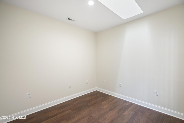 spare room featuring dark wood-type flooring and a skylight