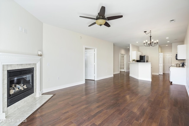 unfurnished living room featuring a fireplace, wood-type flooring, and ceiling fan with notable chandelier