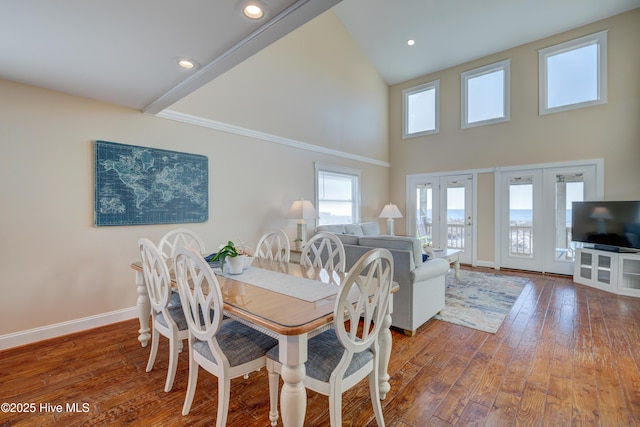 dining space featuring hardwood / wood-style flooring, a towering ceiling, and french doors