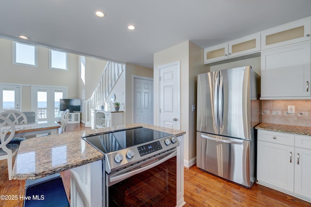 kitchen featuring light stone counters, stainless steel appliances, and white cabinets