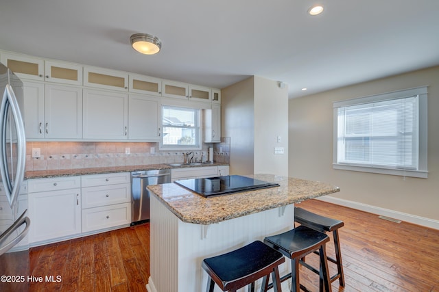 kitchen featuring stainless steel appliances, white cabinetry, a kitchen island, and decorative backsplash