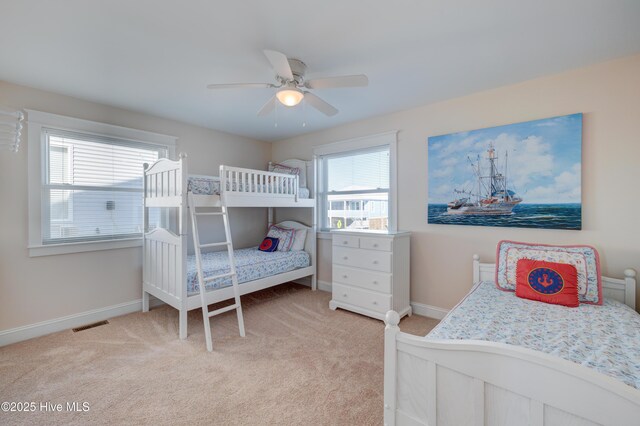 carpeted bedroom featuring multiple windows and ceiling fan