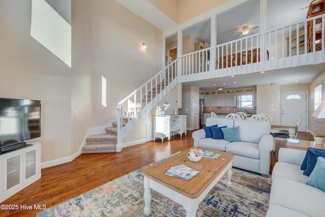 living room featuring ceiling fan, a towering ceiling, and wood-type flooring