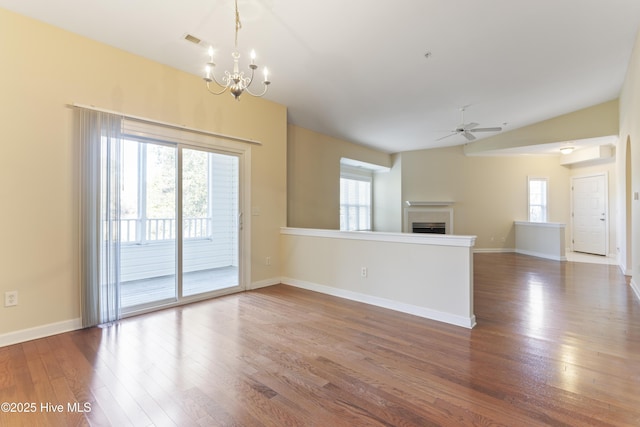 unfurnished living room with lofted ceiling, dark hardwood / wood-style floors, and ceiling fan with notable chandelier