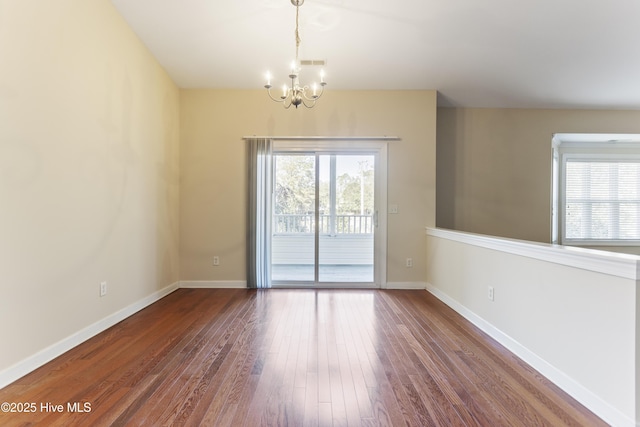 unfurnished room featuring plenty of natural light, a chandelier, and wood-type flooring