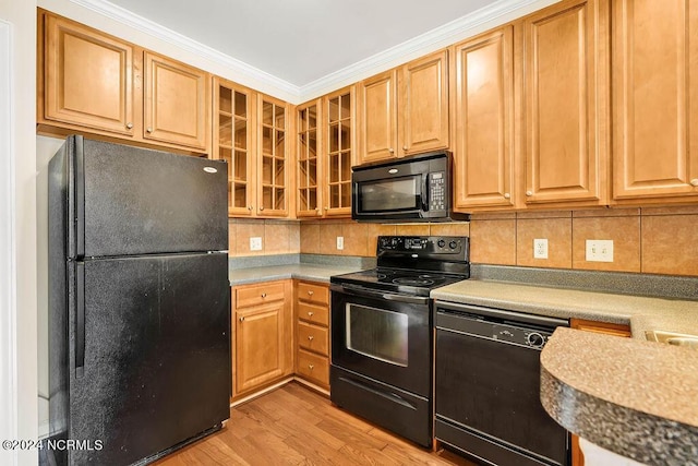 kitchen with crown molding, light hardwood / wood-style flooring, decorative backsplash, and black appliances