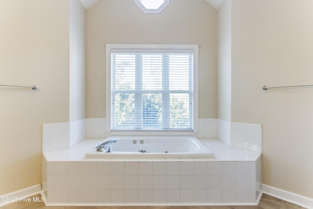 bathroom with tiled tub and lofted ceiling