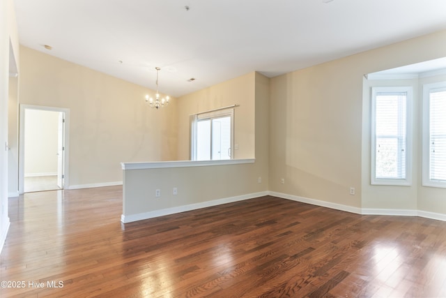 unfurnished room featuring an inviting chandelier, dark wood-type flooring, and lofted ceiling