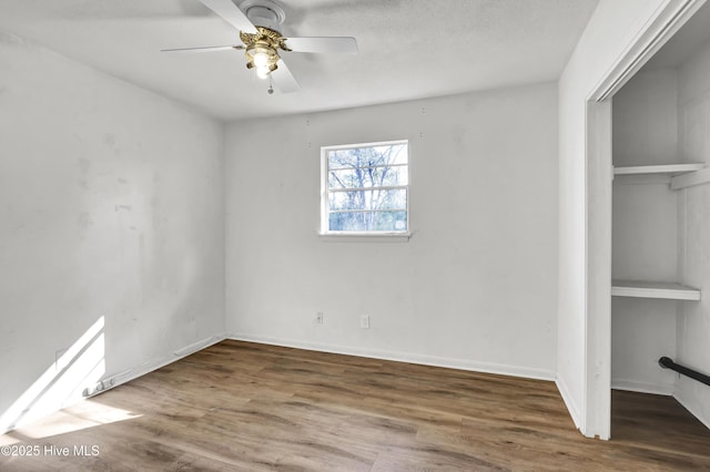 unfurnished bedroom featuring hardwood / wood-style floors, a textured ceiling, ceiling fan, and a closet