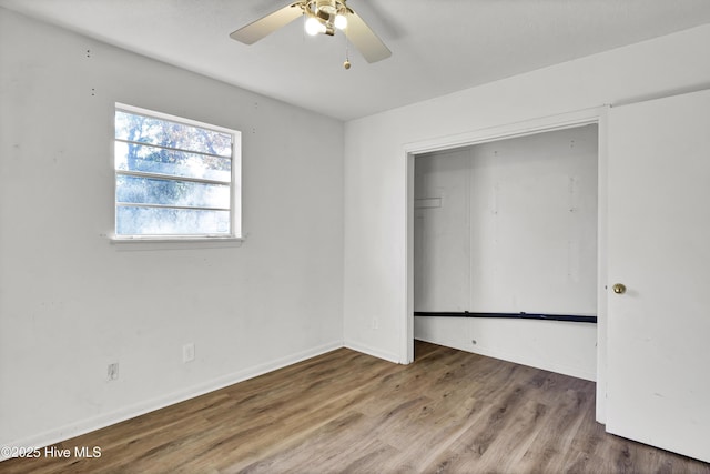 unfurnished bedroom featuring ceiling fan, wood-type flooring, and a closet