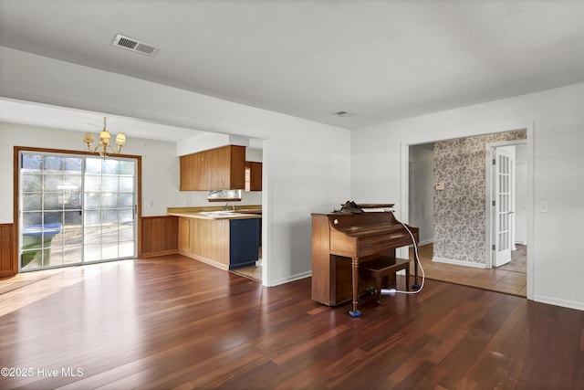 kitchen with dark hardwood / wood-style flooring, kitchen peninsula, and a notable chandelier