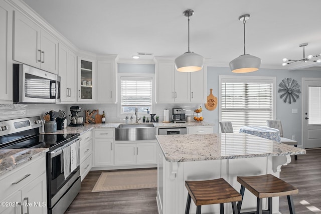 kitchen featuring sink, white cabinetry, hanging light fixtures, and appliances with stainless steel finishes