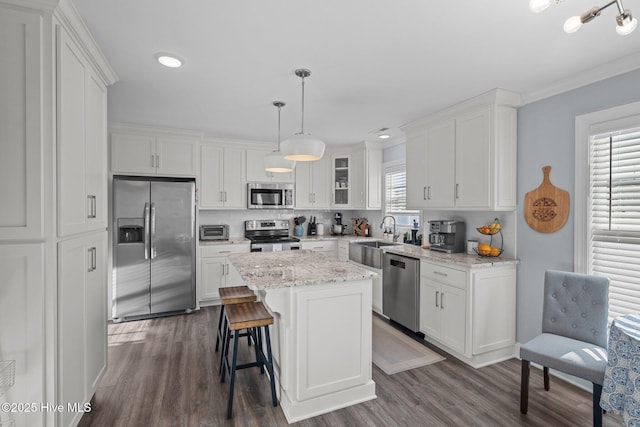 kitchen with a center island, appliances with stainless steel finishes, white cabinetry, hanging light fixtures, and dark hardwood / wood-style flooring