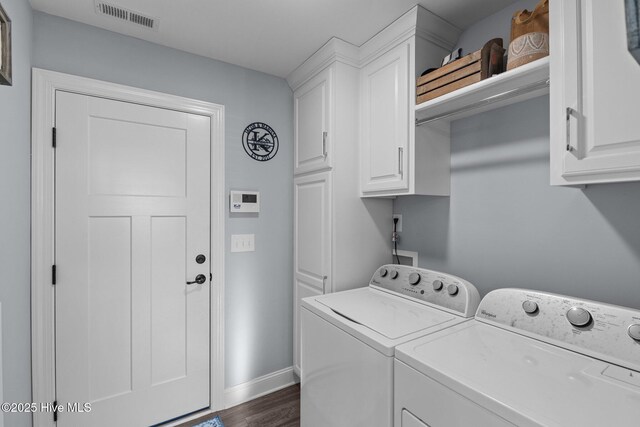 clothes washing area featuring cabinets, separate washer and dryer, and dark hardwood / wood-style flooring