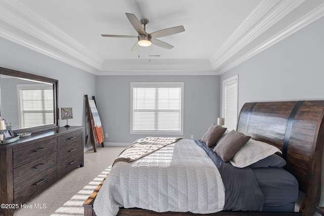 carpeted bedroom with ceiling fan, a tray ceiling, and crown molding