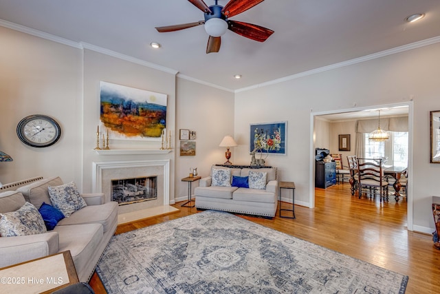 living room with crown molding, a fireplace, light hardwood / wood-style floors, and ceiling fan