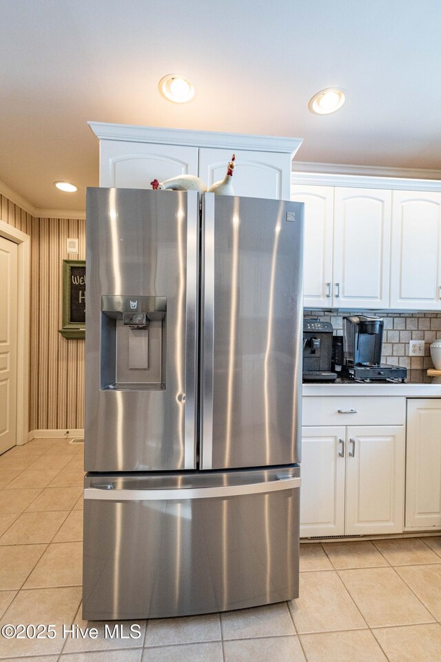 kitchen with white cabinetry, stainless steel refrigerator with ice dispenser, ornamental molding, and light tile patterned floors