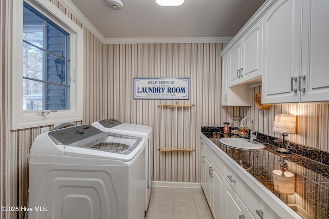 washroom with sink, light tile patterned floors, cabinets, ornamental molding, and washing machine and clothes dryer