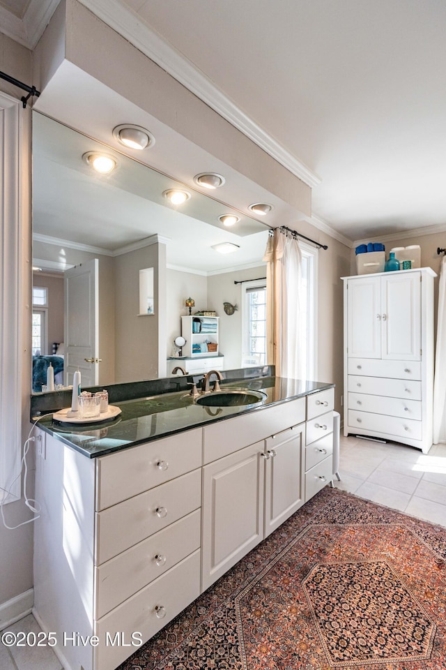 kitchen with light tile patterned flooring, ornamental molding, sink, and white cabinets