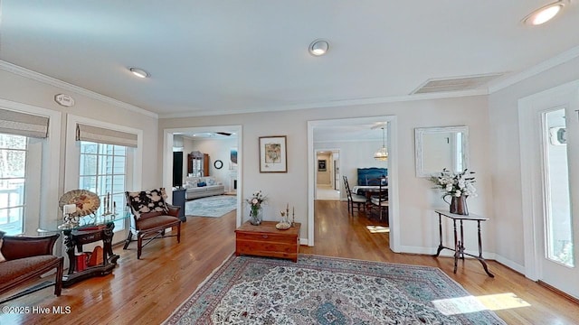sitting room with crown molding, plenty of natural light, and wood-type flooring