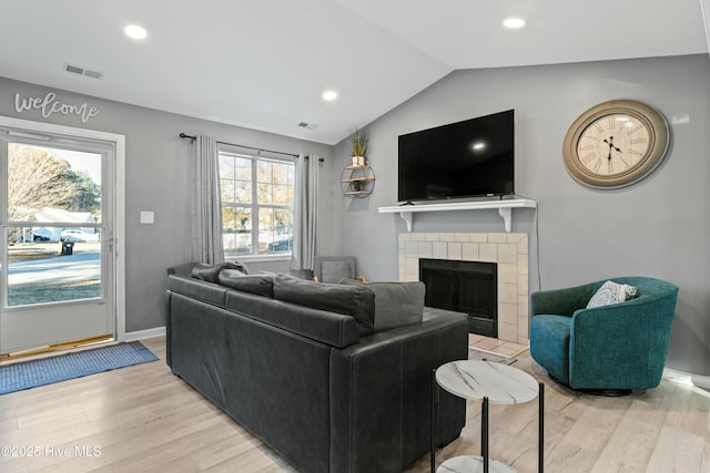 living room with a fireplace, hardwood / wood-style flooring, vaulted ceiling, and a healthy amount of sunlight