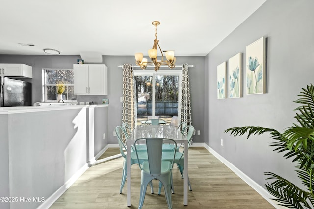 dining space with an inviting chandelier, sink, and light wood-type flooring