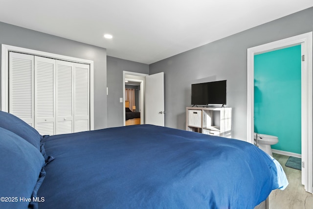 bedroom featuring wood-type flooring, ensuite bath, and a closet