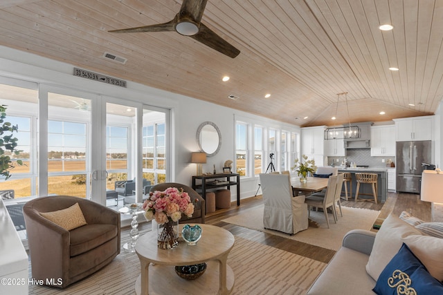 living room with vaulted ceiling, wooden ceiling, ceiling fan, and plenty of natural light