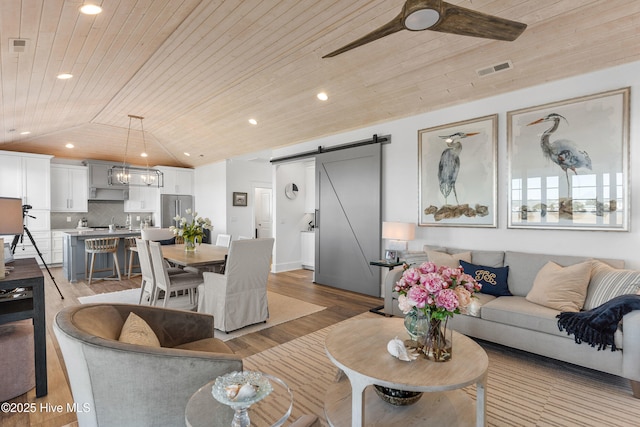 living room featuring ceiling fan, lofted ceiling, a barn door, and wooden ceiling