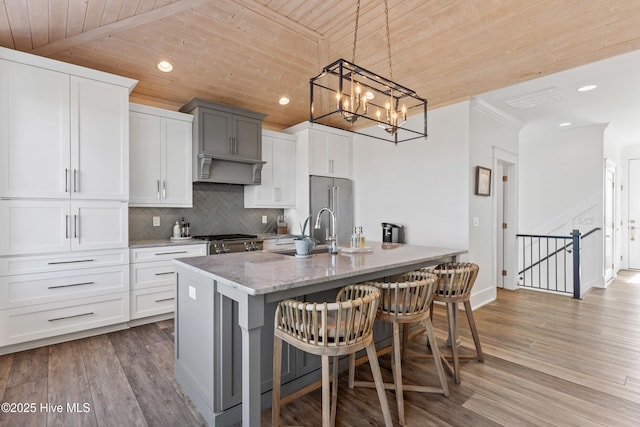 kitchen with decorative light fixtures, white cabinetry, a breakfast bar area, range, and wood ceiling