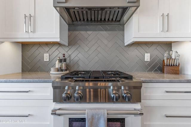 kitchen with tasteful backsplash, white cabinetry, and wall chimney range hood