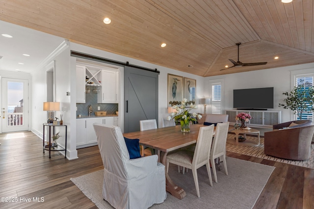 dining room with wood ceiling, a barn door, vaulted ceiling, and hardwood / wood-style flooring