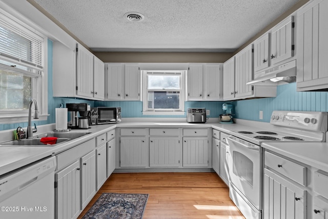 kitchen featuring white cabinetry, white appliances, light hardwood / wood-style floors, and sink