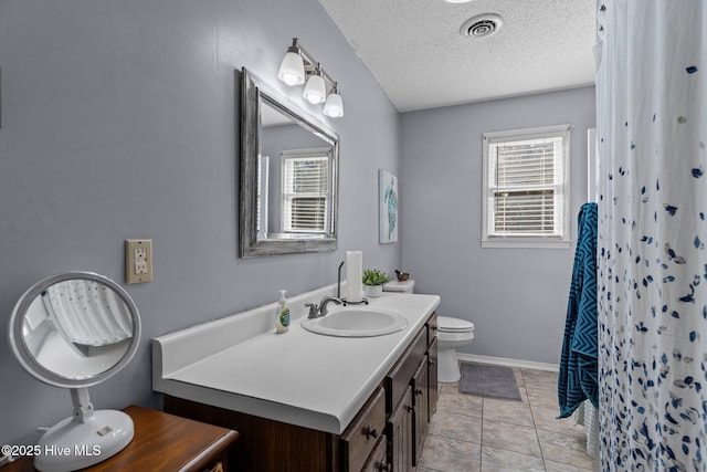 bathroom featuring toilet, a textured ceiling, vanity, curtained shower, and tile patterned flooring