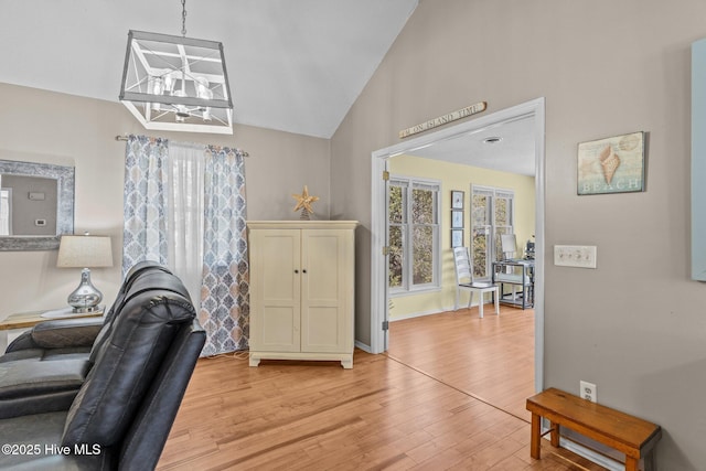 interior space with an inviting chandelier, vaulted ceiling, and light wood-type flooring