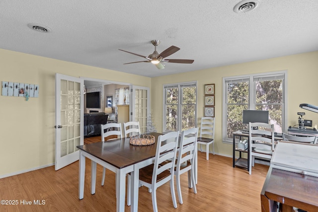 dining room with a textured ceiling, light wood-type flooring, and french doors