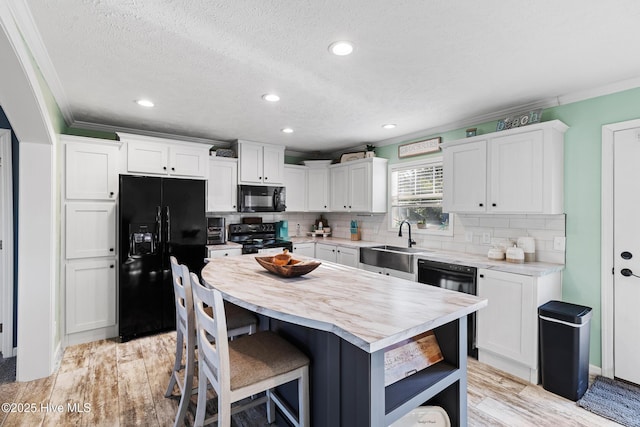 kitchen featuring white cabinets, ornamental molding, a kitchen island, and black appliances