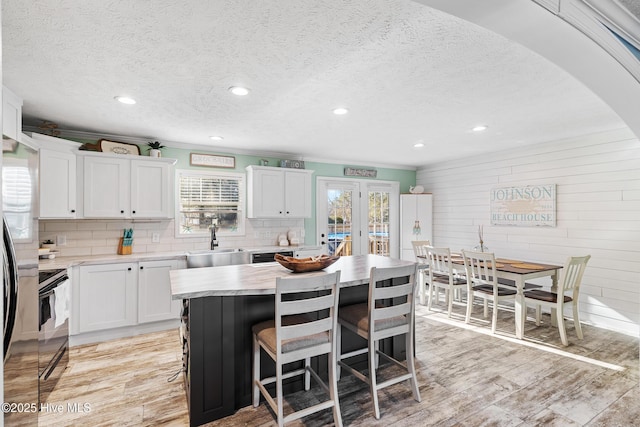 kitchen with sink, a center island, light hardwood / wood-style flooring, a wealth of natural light, and white cabinets