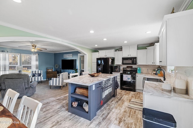 kitchen with sink, white cabinetry, crown molding, a center island, and black appliances