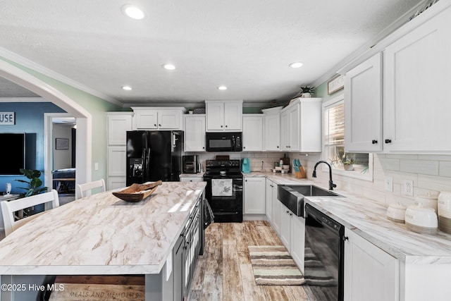 kitchen with white cabinetry, sink, a kitchen island, and black appliances