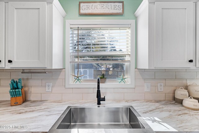 kitchen featuring sink, decorative backsplash, light stone countertops, and white cabinets