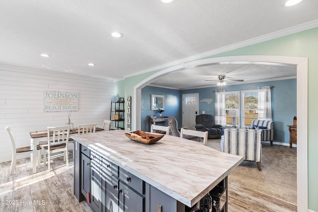 kitchen featuring crown molding, a center island, light hardwood / wood-style flooring, a textured ceiling, and ceiling fan