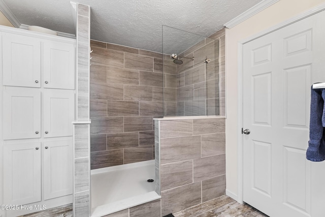 bathroom featuring crown molding, a textured ceiling, and a tile shower